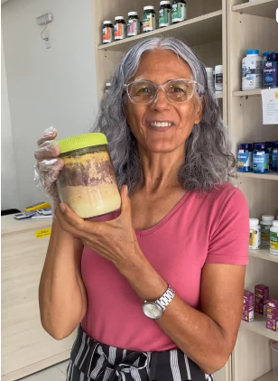 Joana Teles mostrando um pote de produto natural na loja
